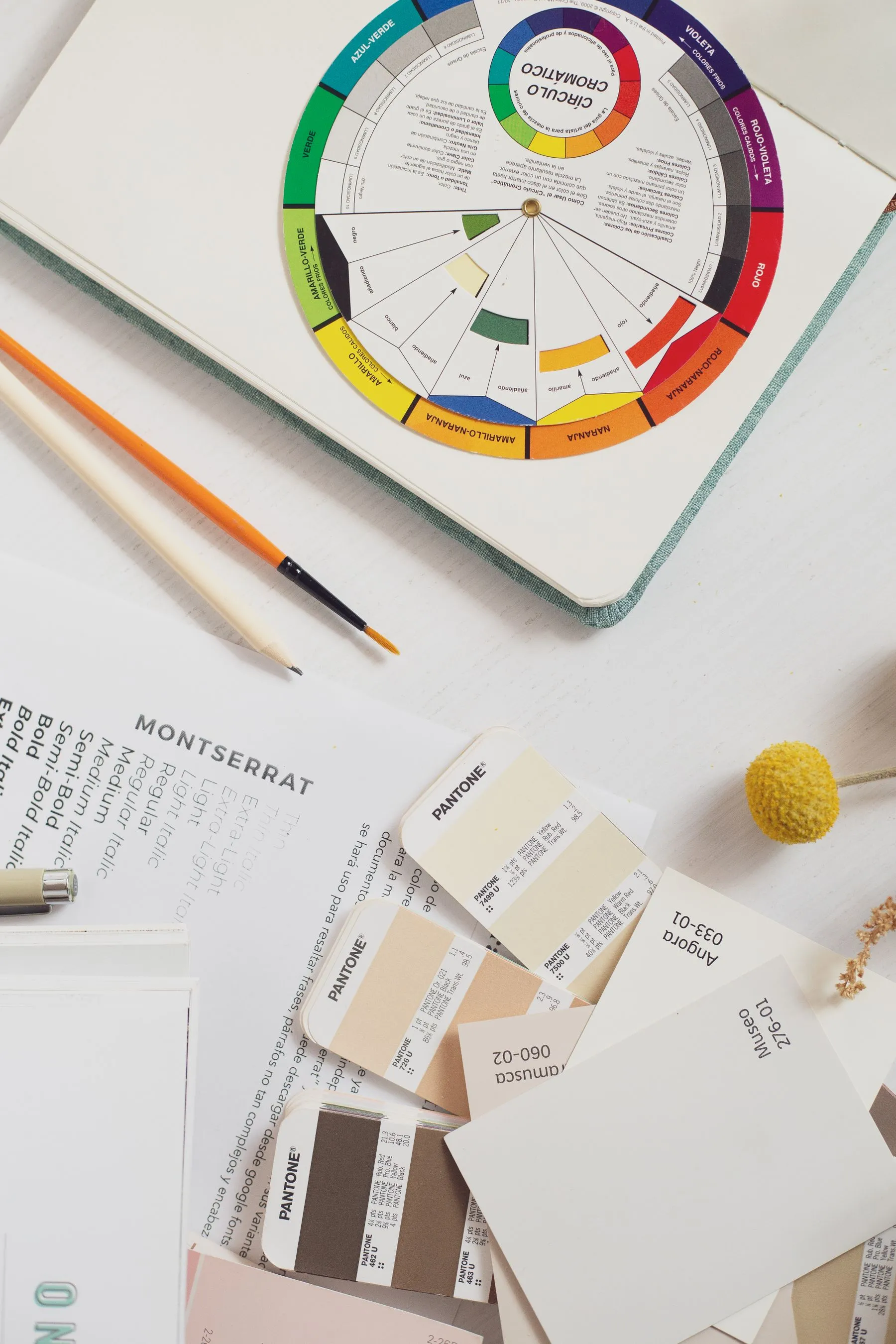Mesa de trabajo de diseño vista desde arriba, con muestras de color y lápices